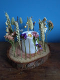 Decorative arrangement of flowers and a candle on a wooden log against a blue background